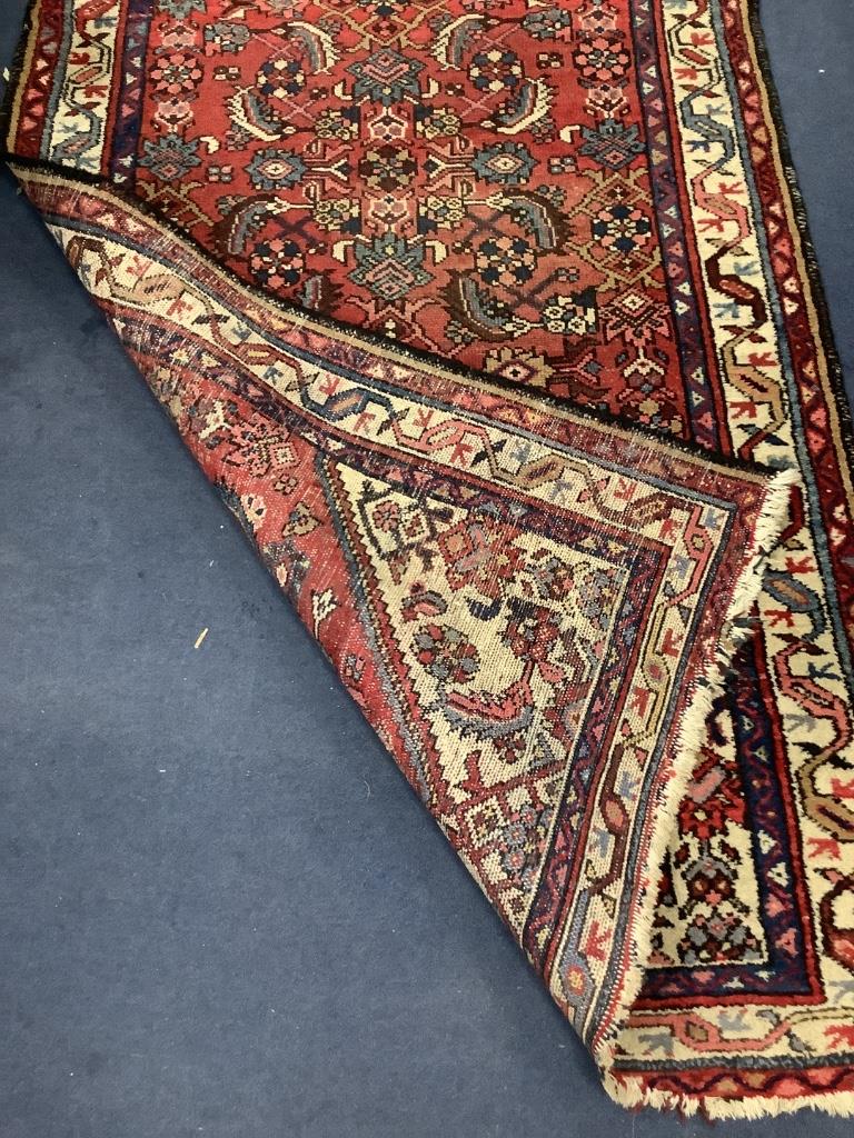 A Caucasian red ground hall carpet, 340 x 102cm